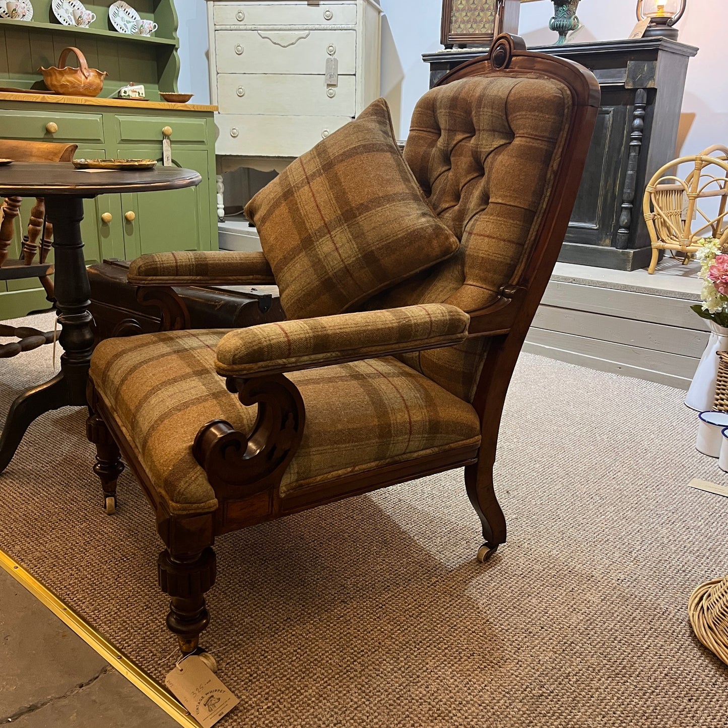 A handsome late Victorian mahogany open armchair, dating from the late 19th century, featuring beautifully carved scroll arms, turned front legs and original brass and ceramic castors.