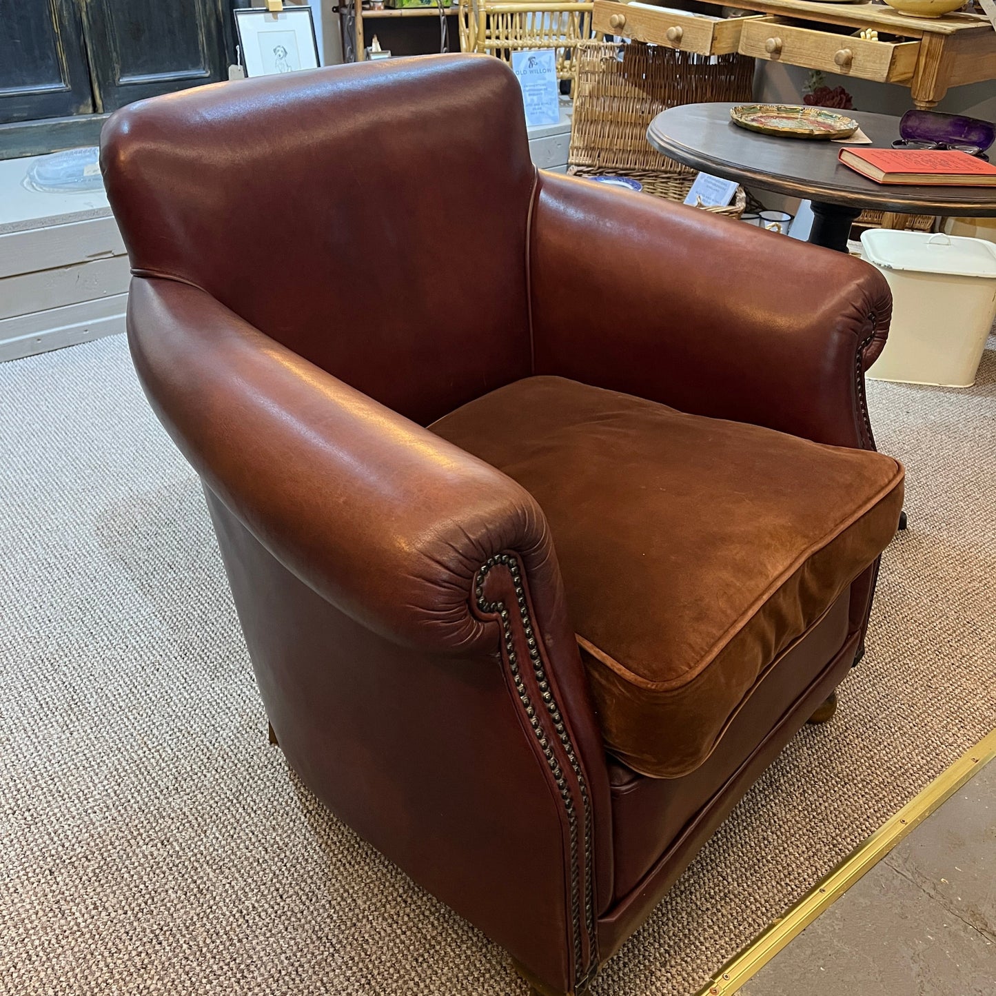 A brown leather club armchair with rolled arms and nailhead trim, 