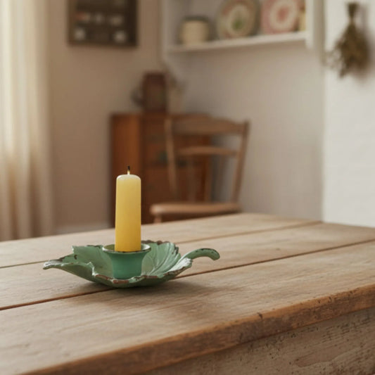 This is a Vintage-Inspired chamber stick candle holder. Made of metal this ivy leaf candle holder has a weathered, rustic, or distressed green patina finish with dark edges. It is made from sturdy cast iron and is designed to hold a single candle. 
