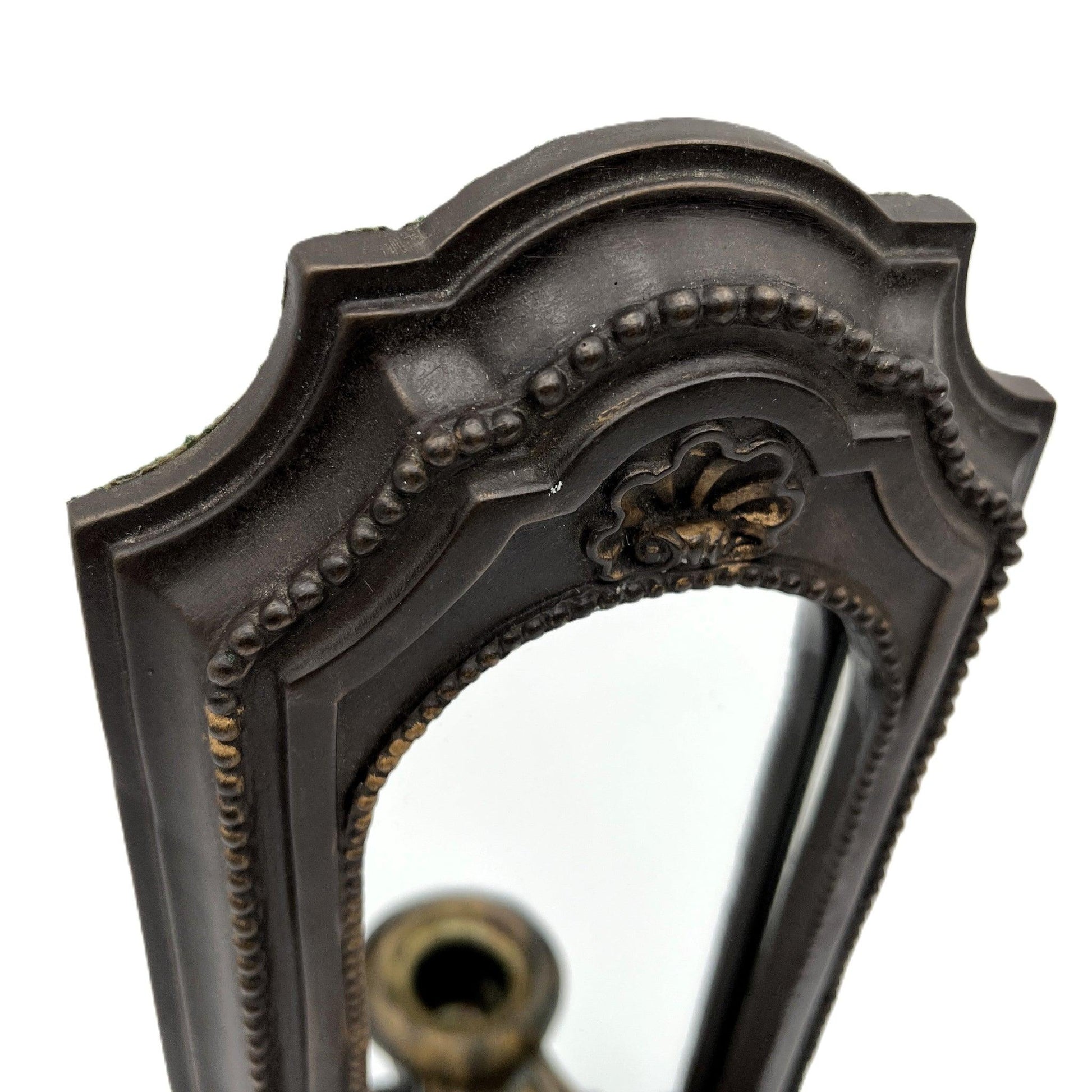 This is a used heavy, vintage-style mirrored wall candle sconce in a bronze-like finish. It has lovely detailing with worn gold accents. It has a felt back with a ring for hanging.