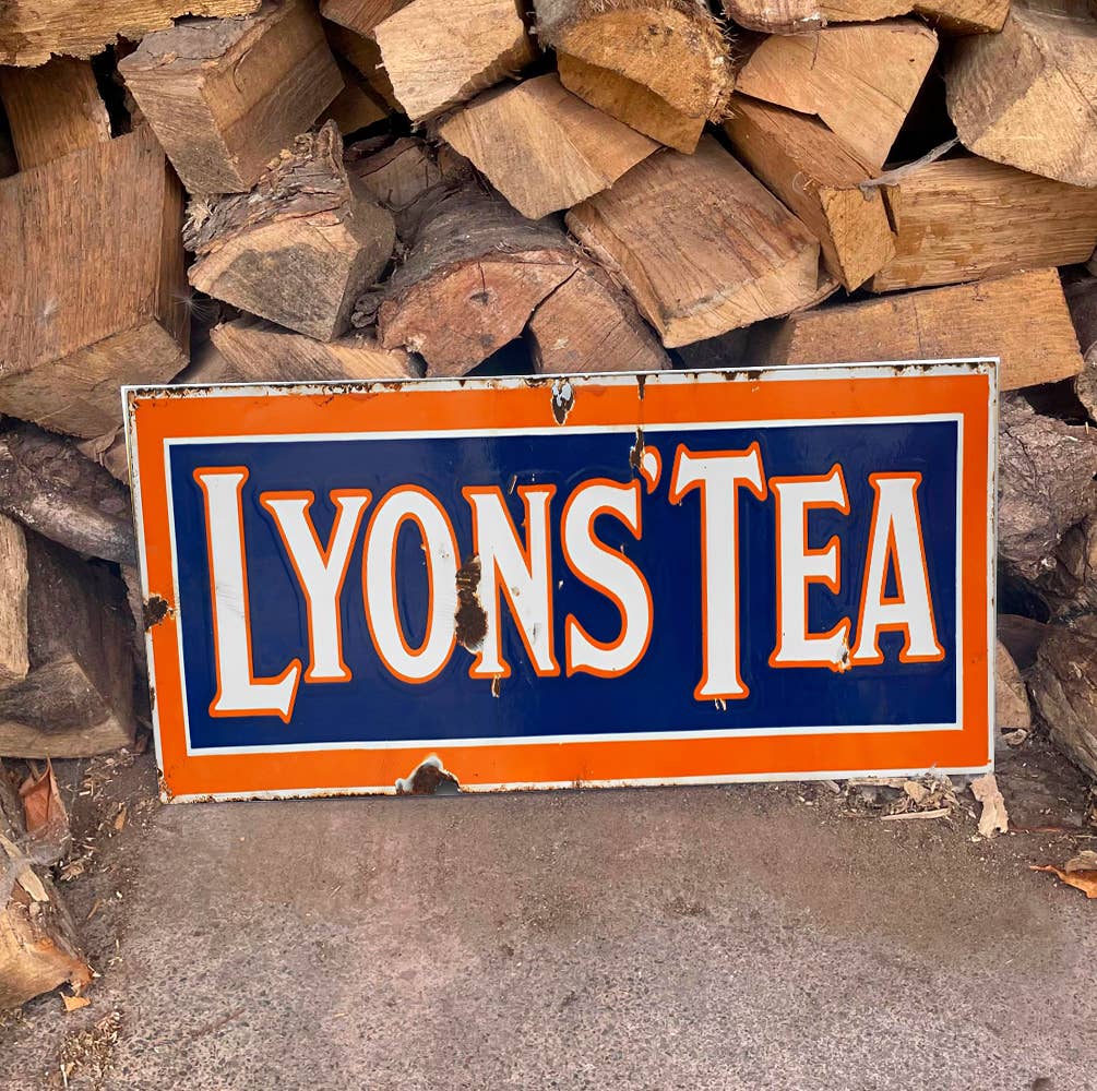 Vintage-style 'Lyons Tea' Sign in front of stacked wooden logs, from Vintage Whippet
