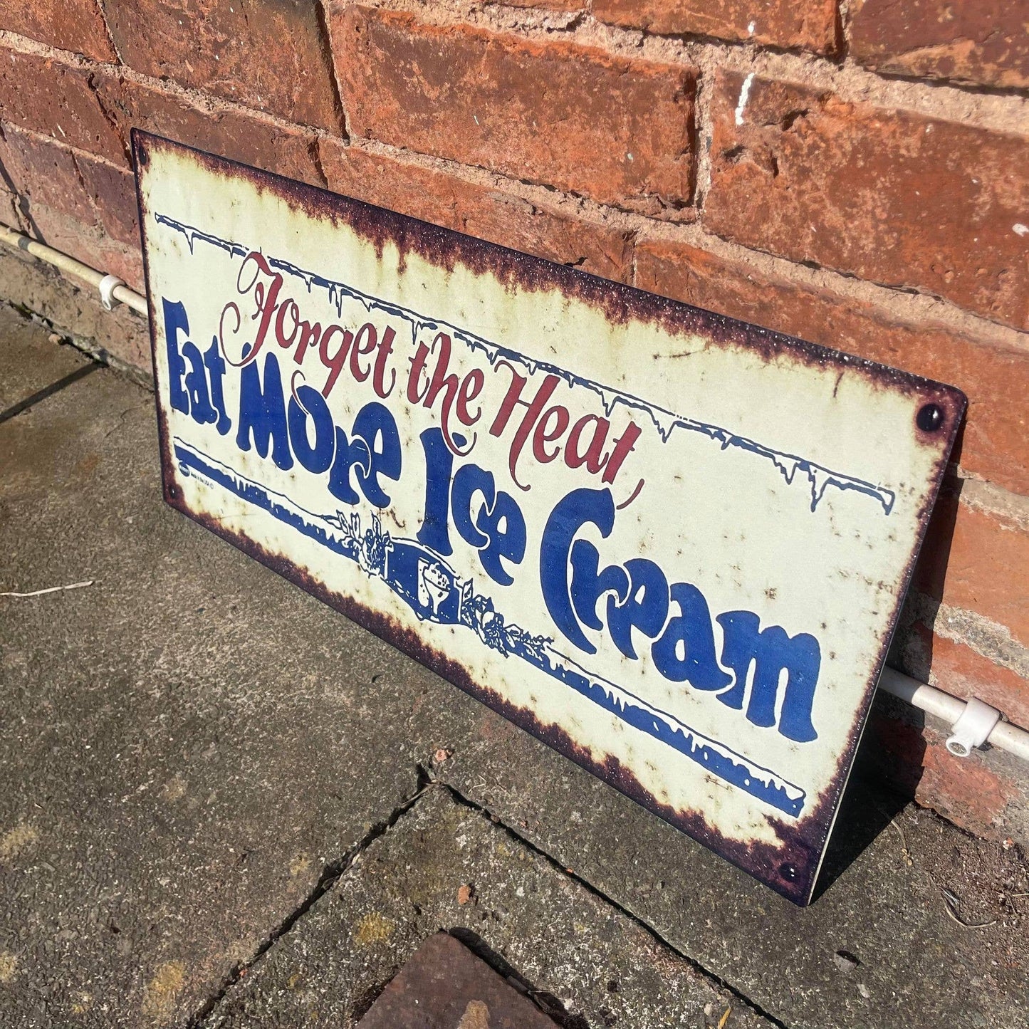 Vintage-style metal sign with text 'Forget the Heat, Eat More Ice Cream' from Vintage Whippet