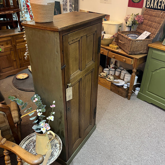 A characterful early 20th-century cupboard featuring a beautifully grained solid oak panelled door complemented by a hand-finished heritage olive-painted carcass
