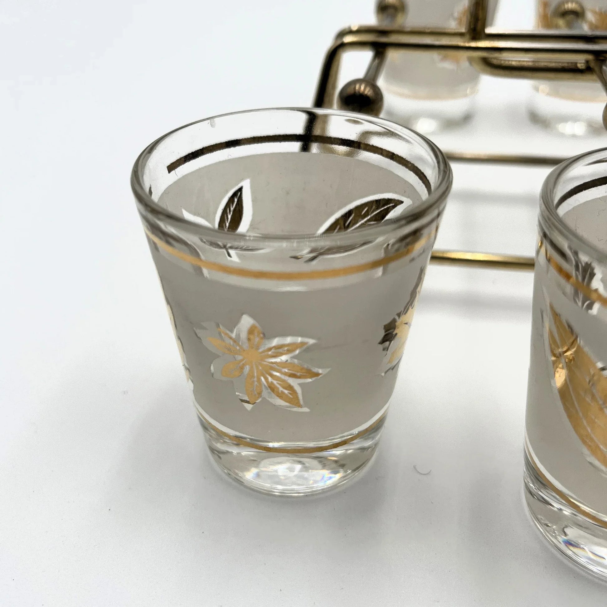 Manufactured in the 1960s, these are a set of 8 vintage Libby frosted gold foil leaf shot glasses, with their own stand.