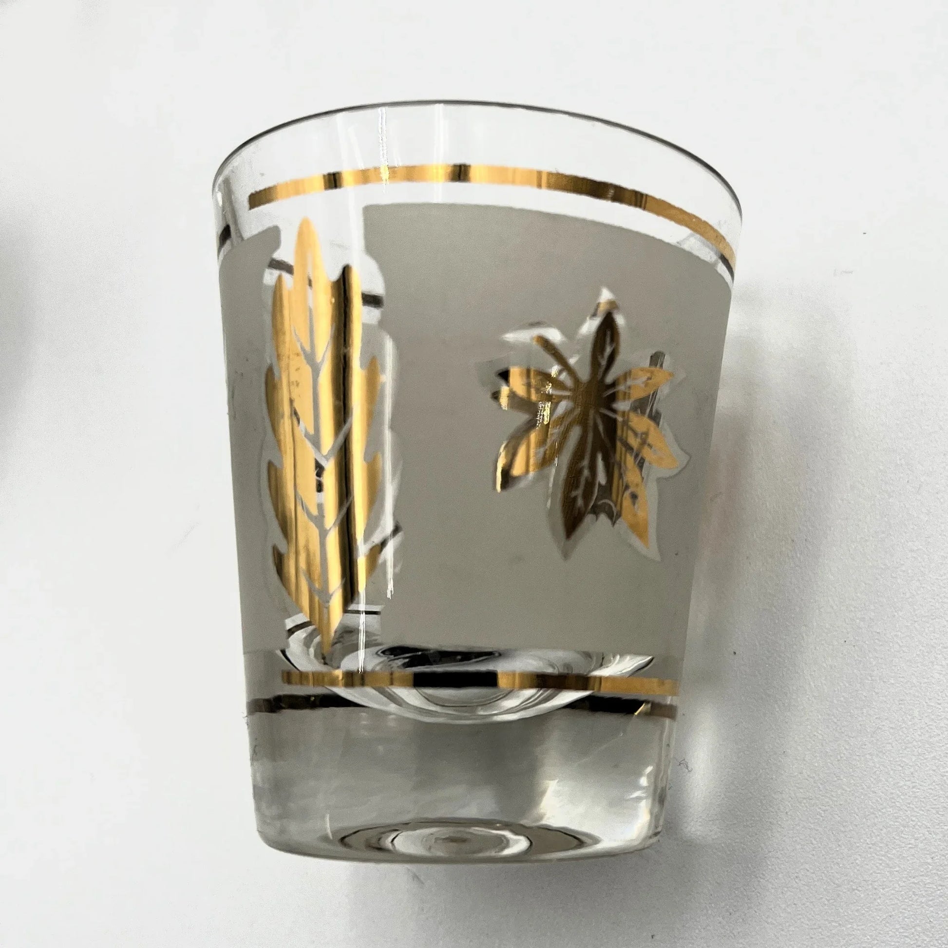 Manufactured in the 1960s, these are a set of 8 vintage Libby frosted gold foil leaf shot glasses, with their own stand.