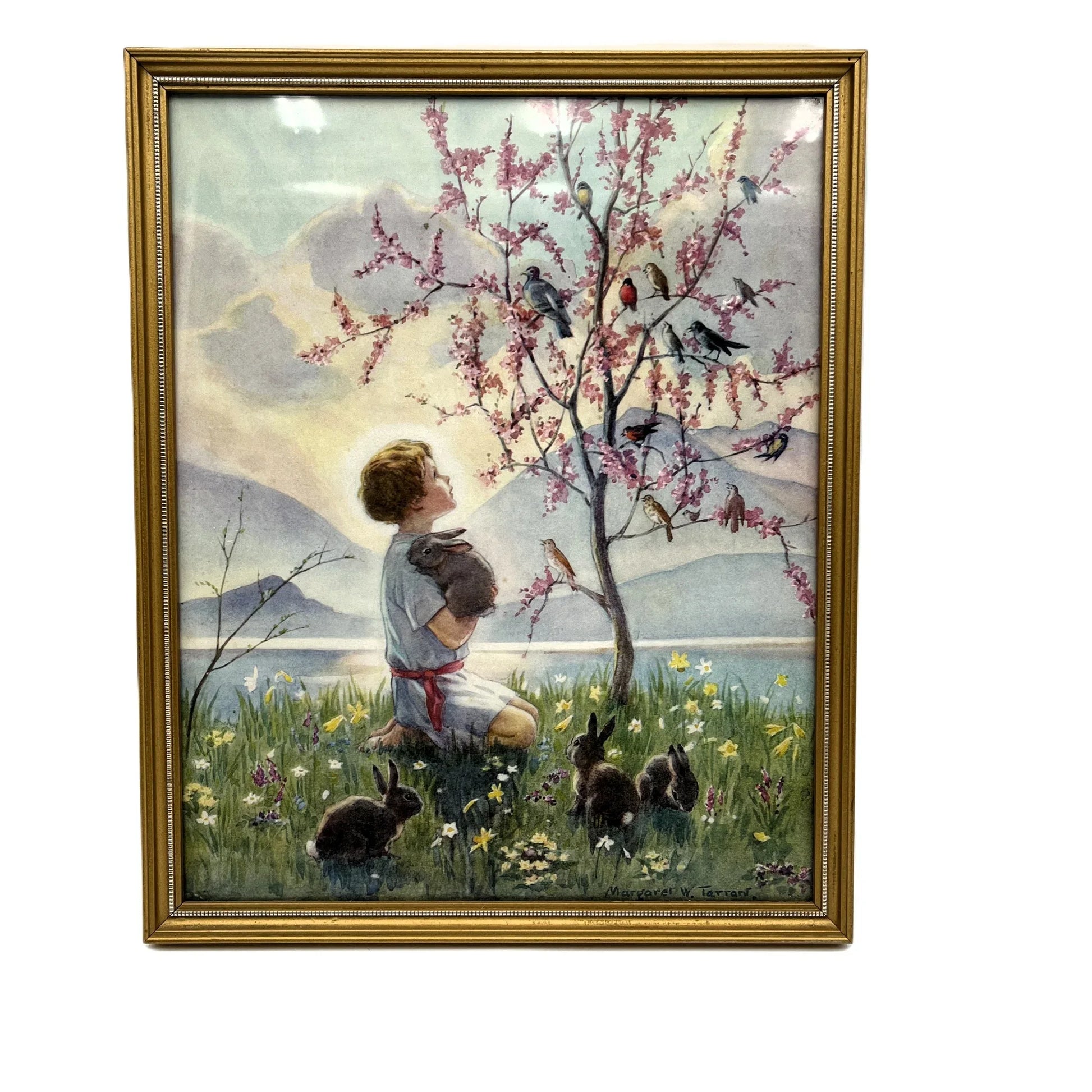 This is a framed print of the painting "Morning Carol" by the British illustrator Margaret Tarrant (1888-1959). The artwork depicts a child holding a rabbit, surrounded by other rabbits and birds under a blossoming tree, in a pastoral setting. 