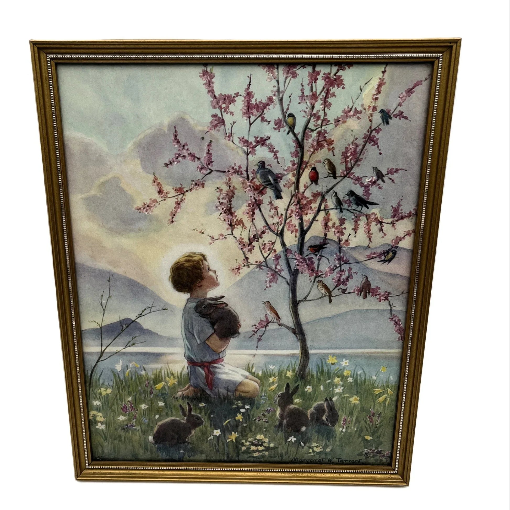 This is a framed print of the painting "Morning Carol" by the British illustrator Margaret Tarrant (1888-1959). The artwork depicts a child holding a rabbit, surrounded by other rabbits and birds under a blossoming tree, in a pastoral setting. 